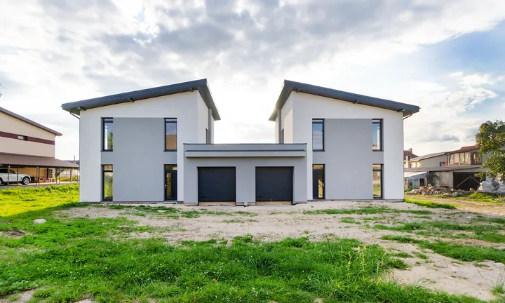 Two completed modern houses side by side under a bright sky
