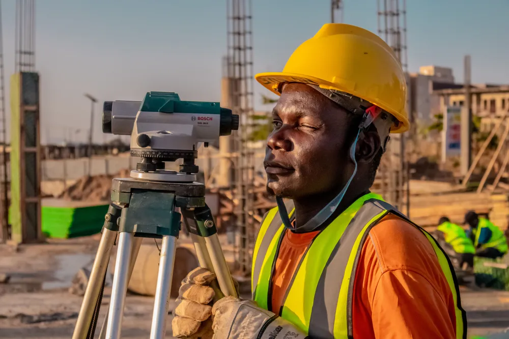 Surveyor sighting through a total station mounted on a tripod on open ground